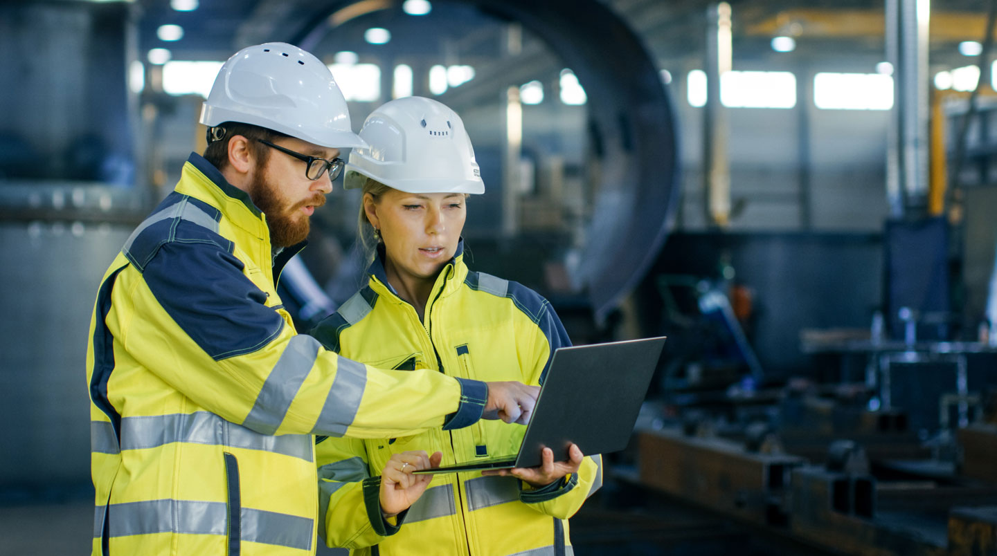Technicienne de maintenance consultant sur tablette un dashboard de prédiction IA affichant alertes et interventions planifiées en atelier industriel