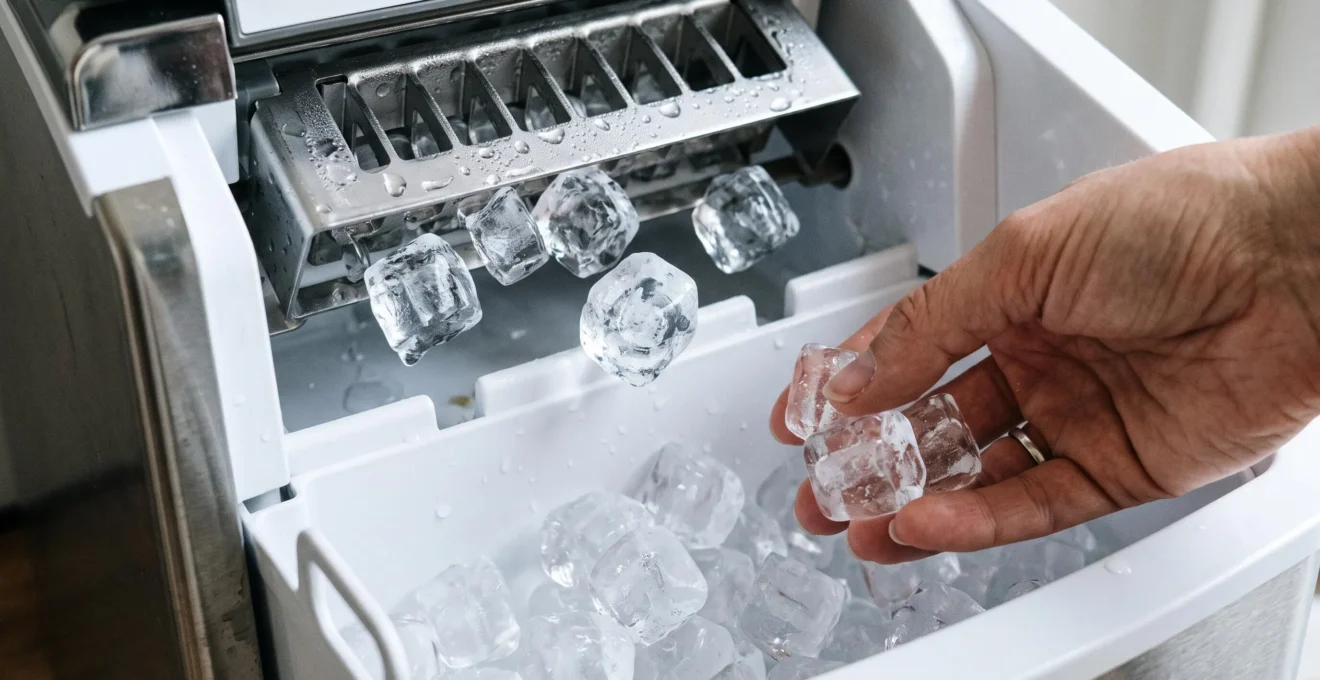 Gros plan sur des glaçons transparents tombant dans le bac de collecte d'une machine à glaçons